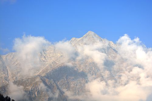 Free Stunning view of a mountain peak surrounded by clouds against a clear blue sky. Stock Photo