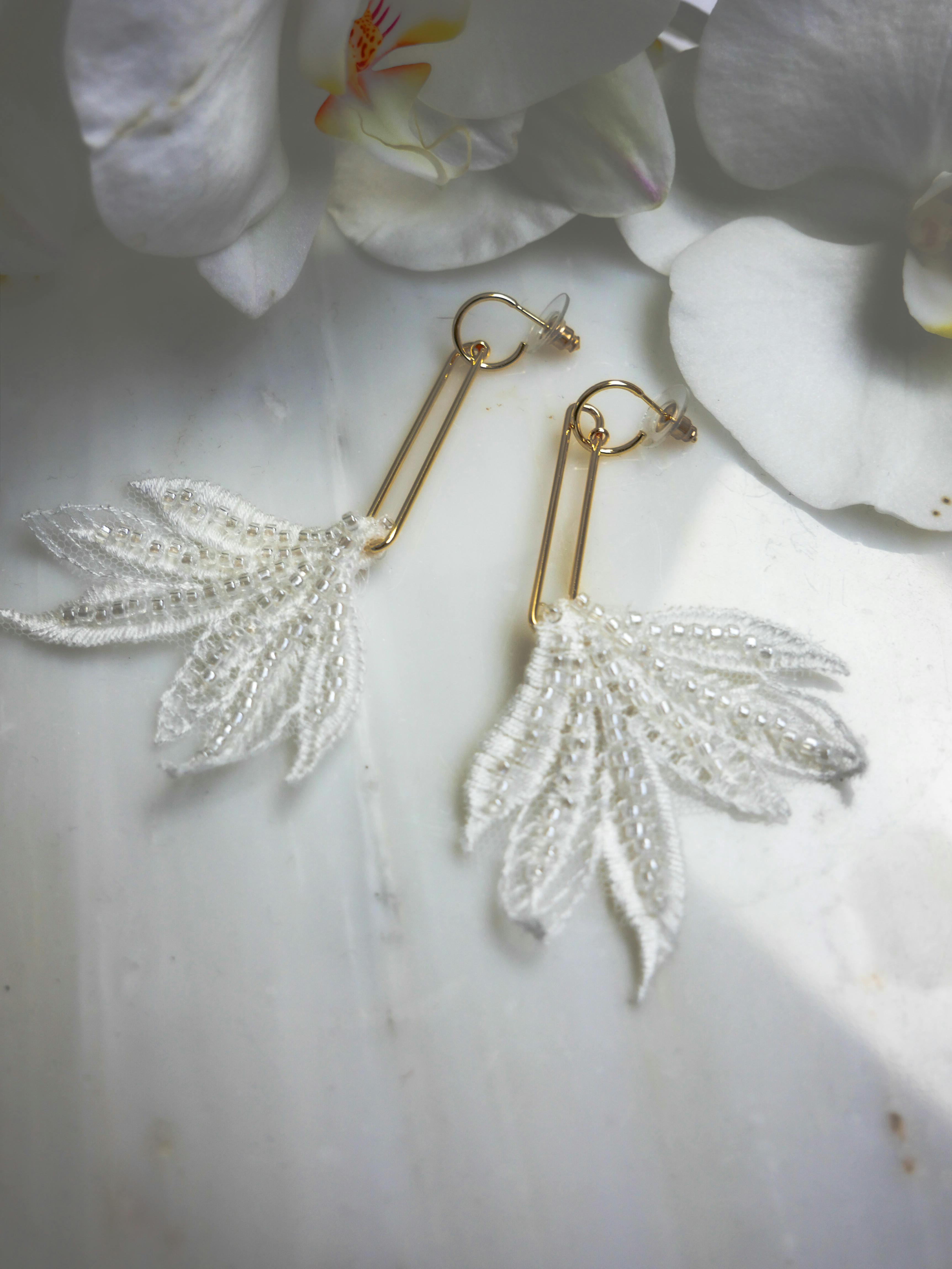 gold and silver earrings on white textile