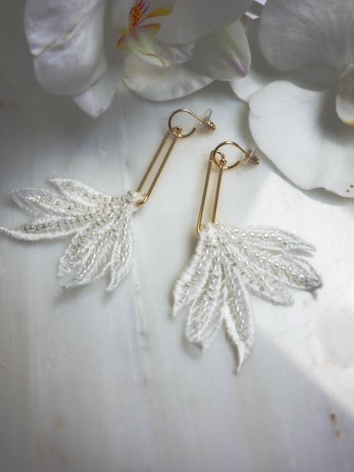 Gold and Silver Earrings on White Textile