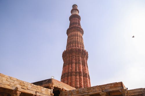 From below of ancient ornamental brick tower of Qutb Minar against cloudless blue sky located in historic complex in Delhi