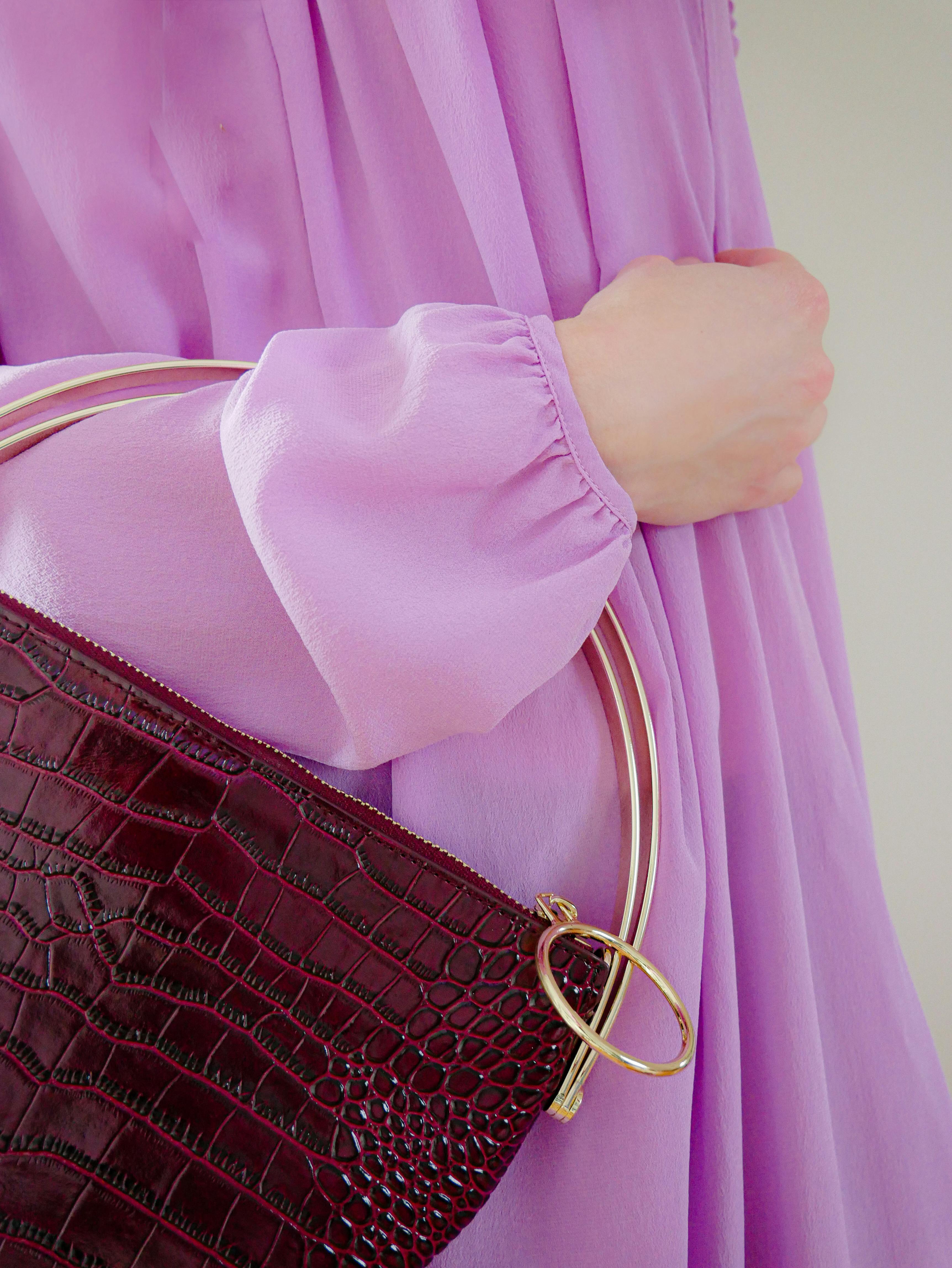 紫色连衣裙搭配棕色手提包，细节处展现优雅时尚感