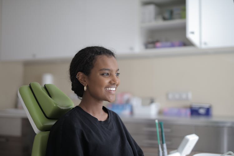 Smiling Young Ethnic Female Patient Sitting In Dental Chair In Modern Clinic