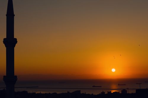 Free A breathtaking sunset over Samsun, Türkiye, silhouetting a minaret and ships on the horizon. Stock Photo