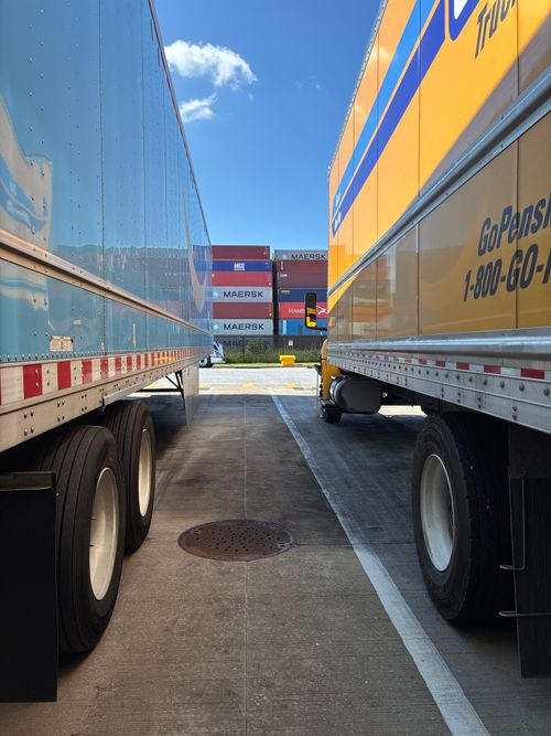 Parked trailers and shipping containers in sunny lot