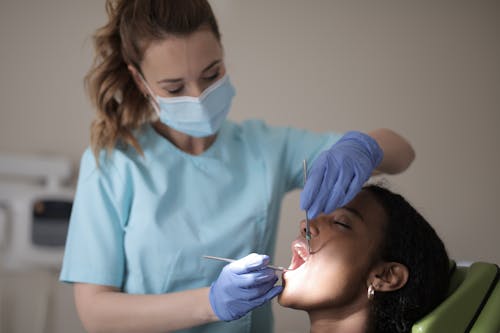 Young female dentist treating teeth of female patient in modern clinic