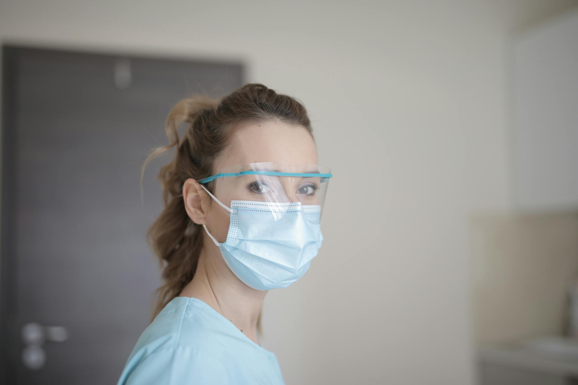 Portrait of a female healthcare worker in protective gear including face mask and shield.