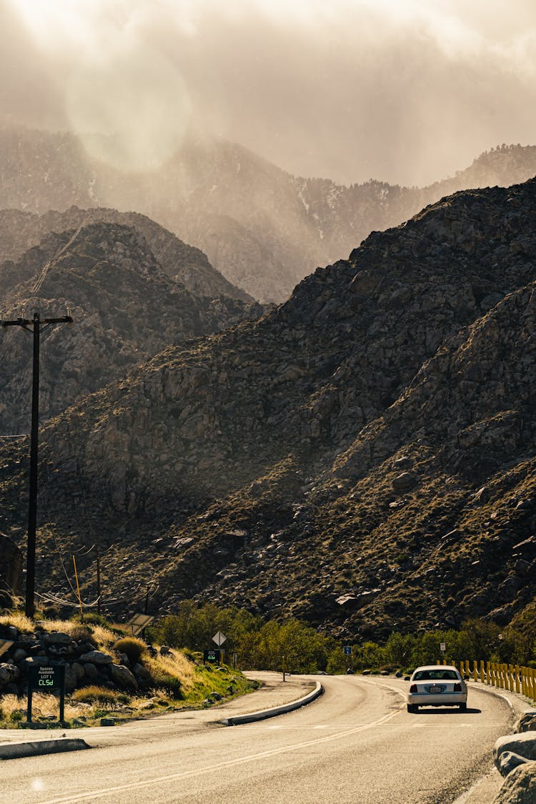 A Car On The Road Beside Rocky Mountains