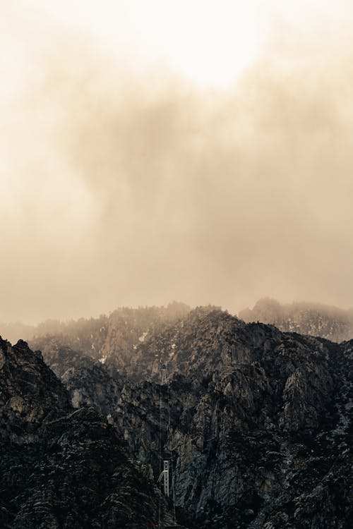 Free Breathtaking landscape of rocky mountains under misty clouds floating over high peaks on overcast day Stock Photo