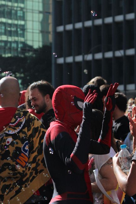 Vibrant street scene in São Paulo with people celebrating, including a Spider-Man cosplayer.