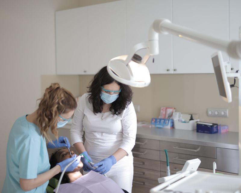 A dentist and assistant treating a young patient's tooth in a modern clinic