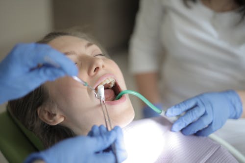 Unrecognizable dentists using medical equipment during teeth treatment in modern clinic
