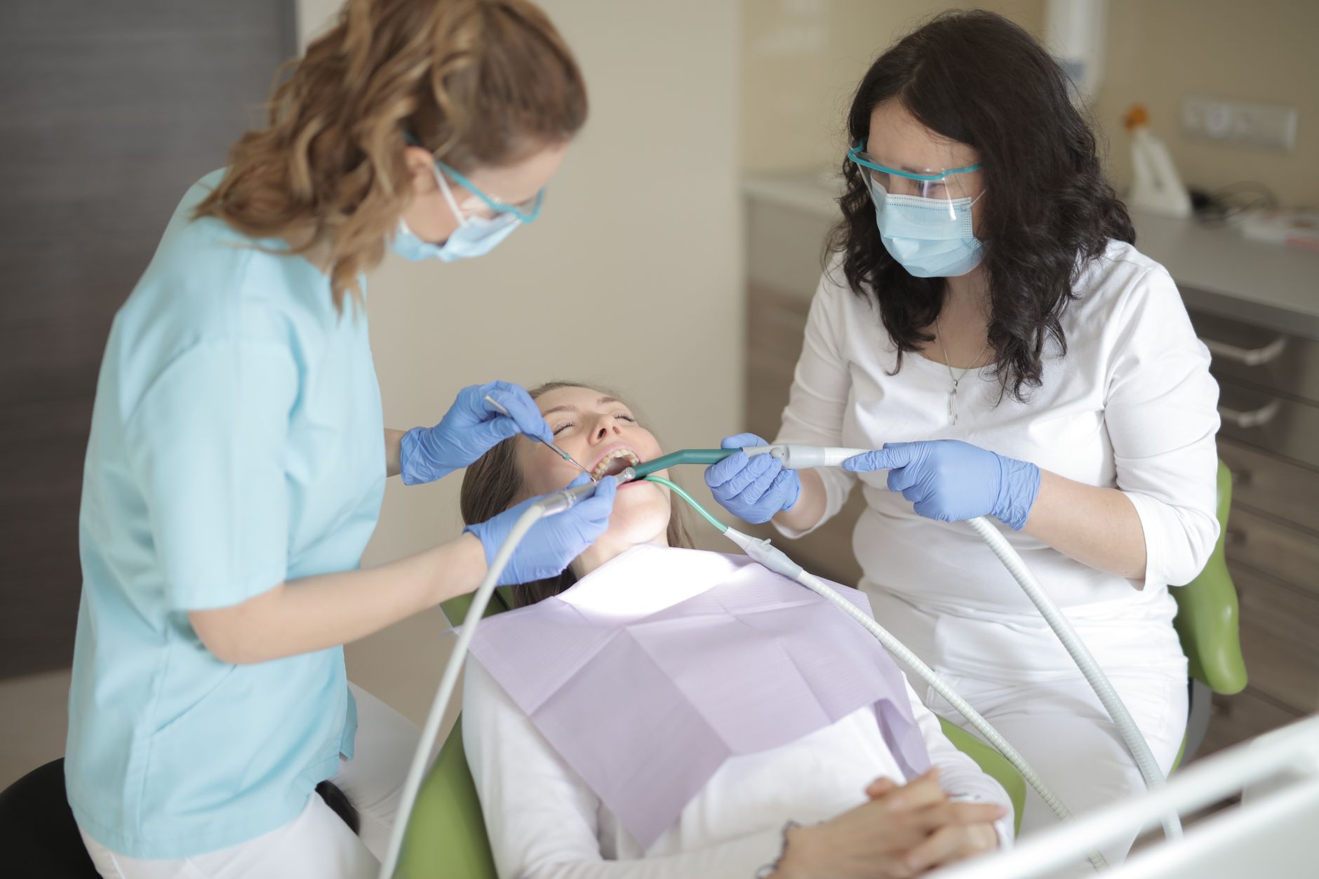 Dentists providing professional dental care to a patient in a sterile clinic environment.