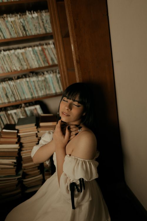 Free A peaceful woman enjoying a quiet moment in a cozy library setting. Stock Photo