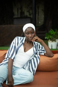 Fashionable woman in casual attire relaxing on a sofa indoors, exuding elegance and style.
