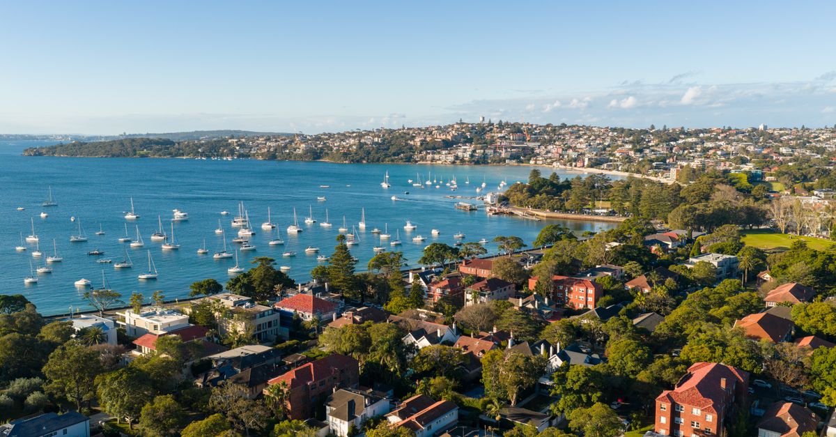Aerial perspective of Sydney's beautiful harbor with yachts and residential areas on a sunny day.