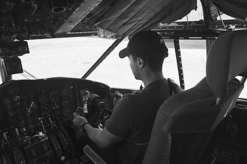 Grayscale Photo of Man Flying A Plane