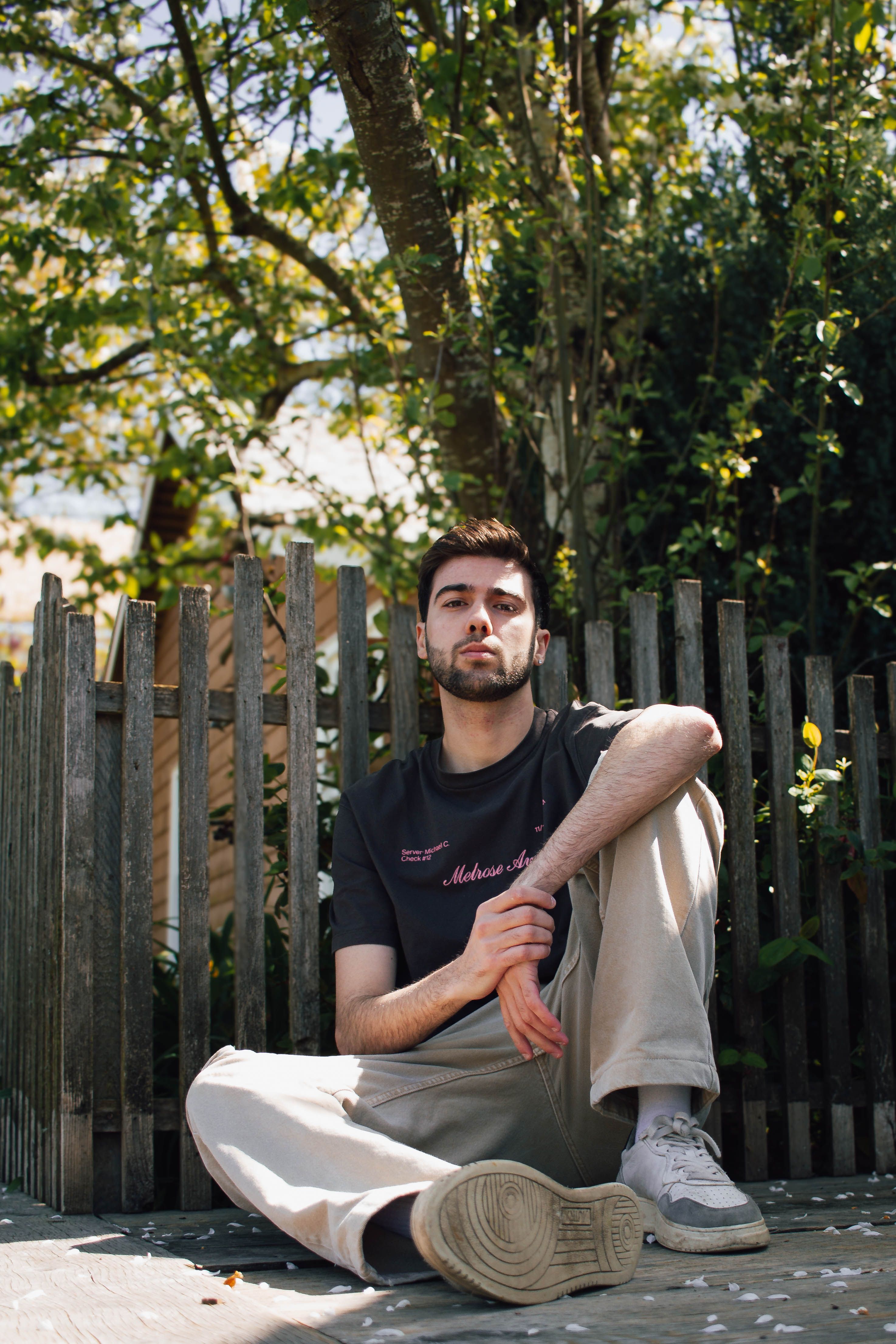 A relaxed portrait of a young adult man sitting outdoors in a sunny Vancouver location.