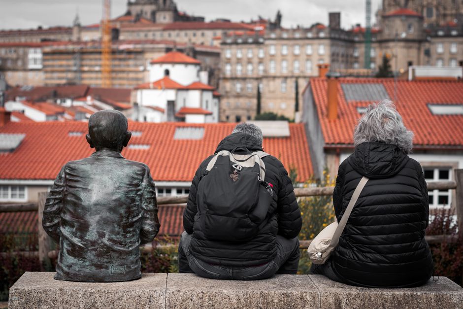 Dos ancianos y una estatua contemplan el paisaje urbano de Santiago de Compostela, España.
