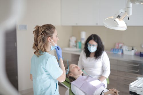 Free Female dentists working with patient in modern clinic Stock Photo