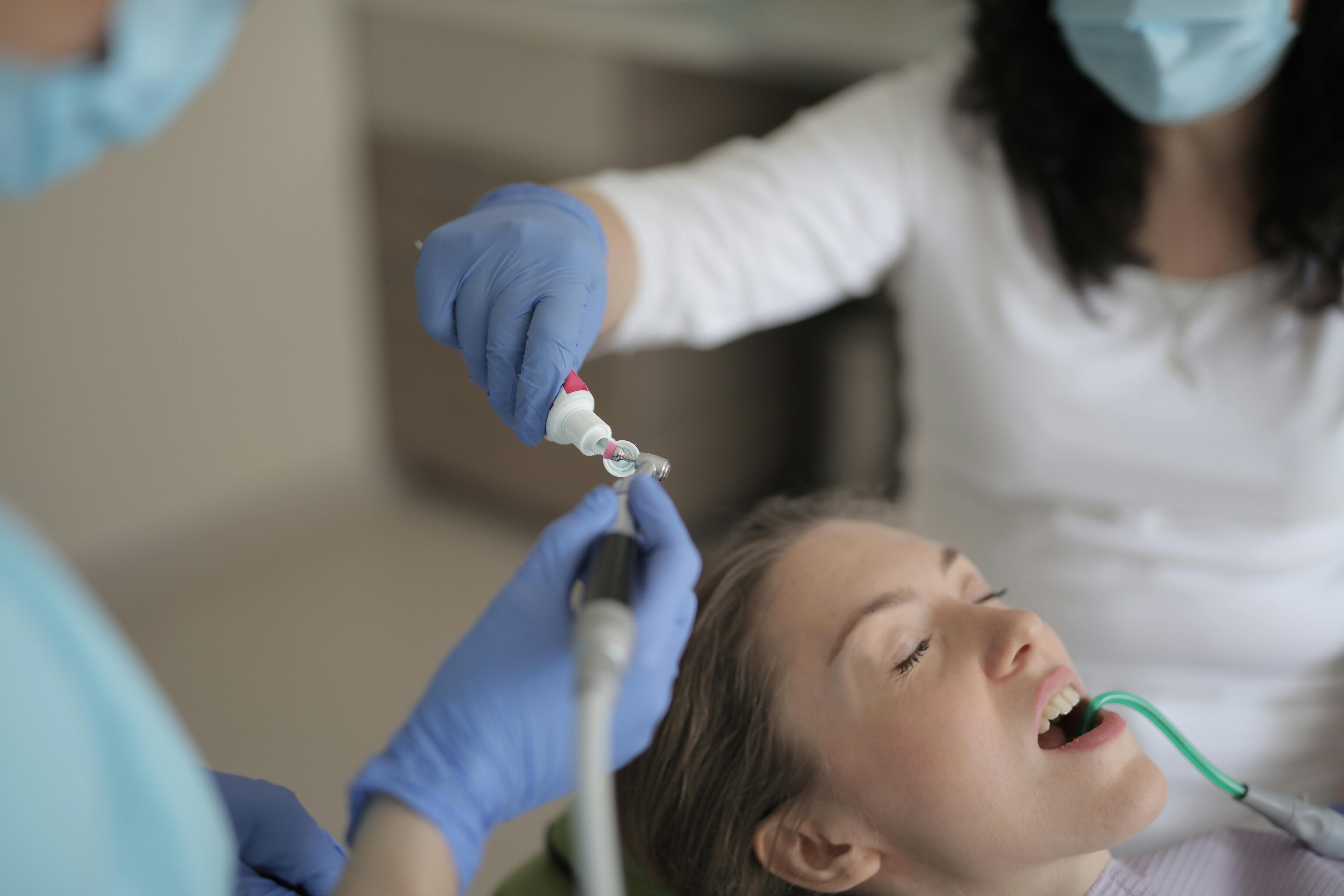 Cheerful young female dentist talking with patient during therapy in ...