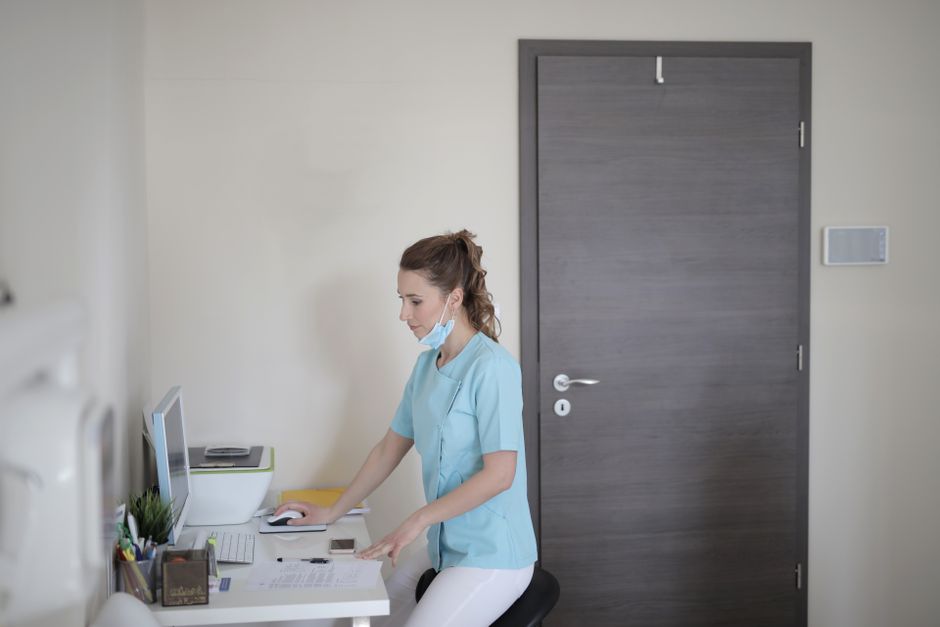 Trabajadora de la salud femenina enfocada en clínica usando ordenador en moderna configuración de escritorio.