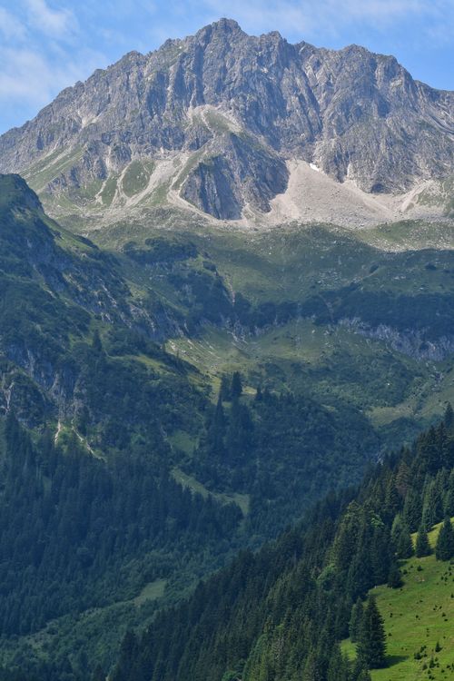 Free Breathtaking view of an Alpine mountain with lush green valleys and rocky peaks. Stock Photo
