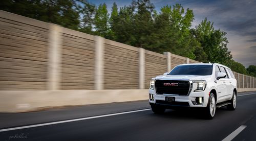 Free A white GMC Yukon XL drives on a highway in Charlotte, showcasing speed and modern design. Stock Photo