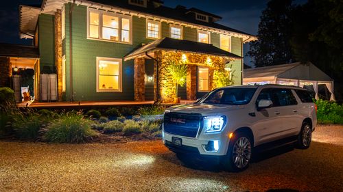 Free A white luxury SUV parked in front of an illuminated mansion at night in Charlotte. Stock Photo