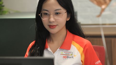 Bank teller in uniform at desk assisting customers, creating a friendly atmosphere.
