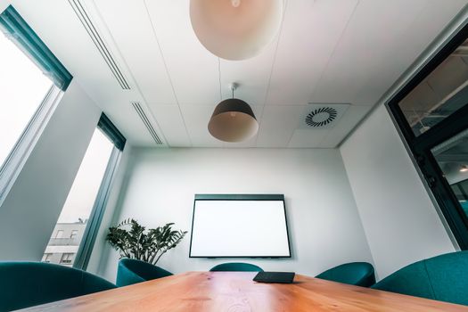 Spacious, bright conference room featuring a blank screen, ideal for presentations or meetings.