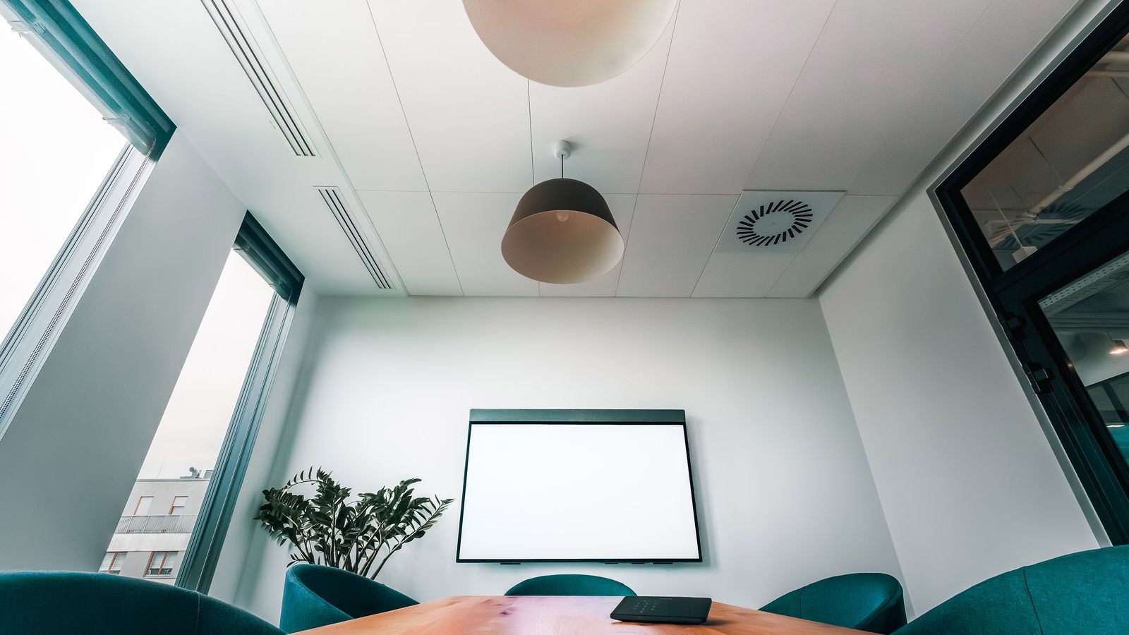 Spacious, bright conference room featuring a blank screen, ideal for presentations or meetings.