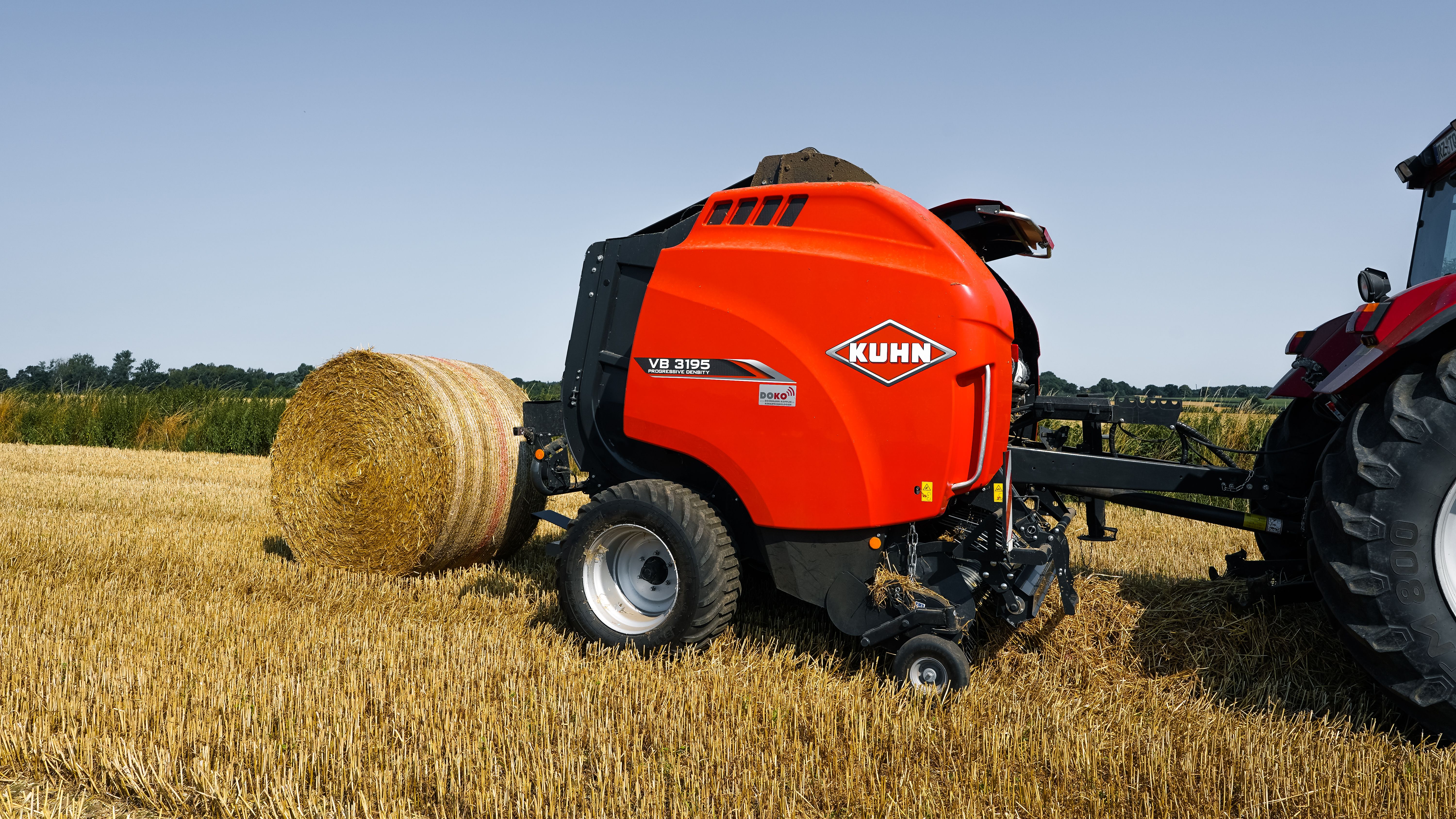 Bright summer day on a Schleswig-Holstein farm with a baler creating straw bales. Perfect for agricultural themes.