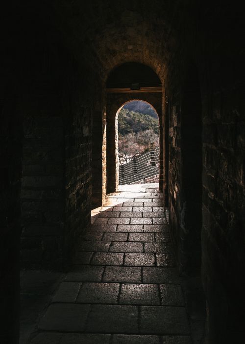 Free A dark passageway leading to an outdoor view, featuring architectural arches. Stock Photo