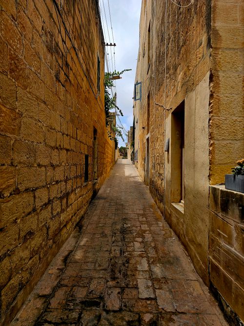 Free A narrow cobbled alleyway between old stone buildings in a historic Mediterranean town, showcasing classic architecture. Stock Photo
