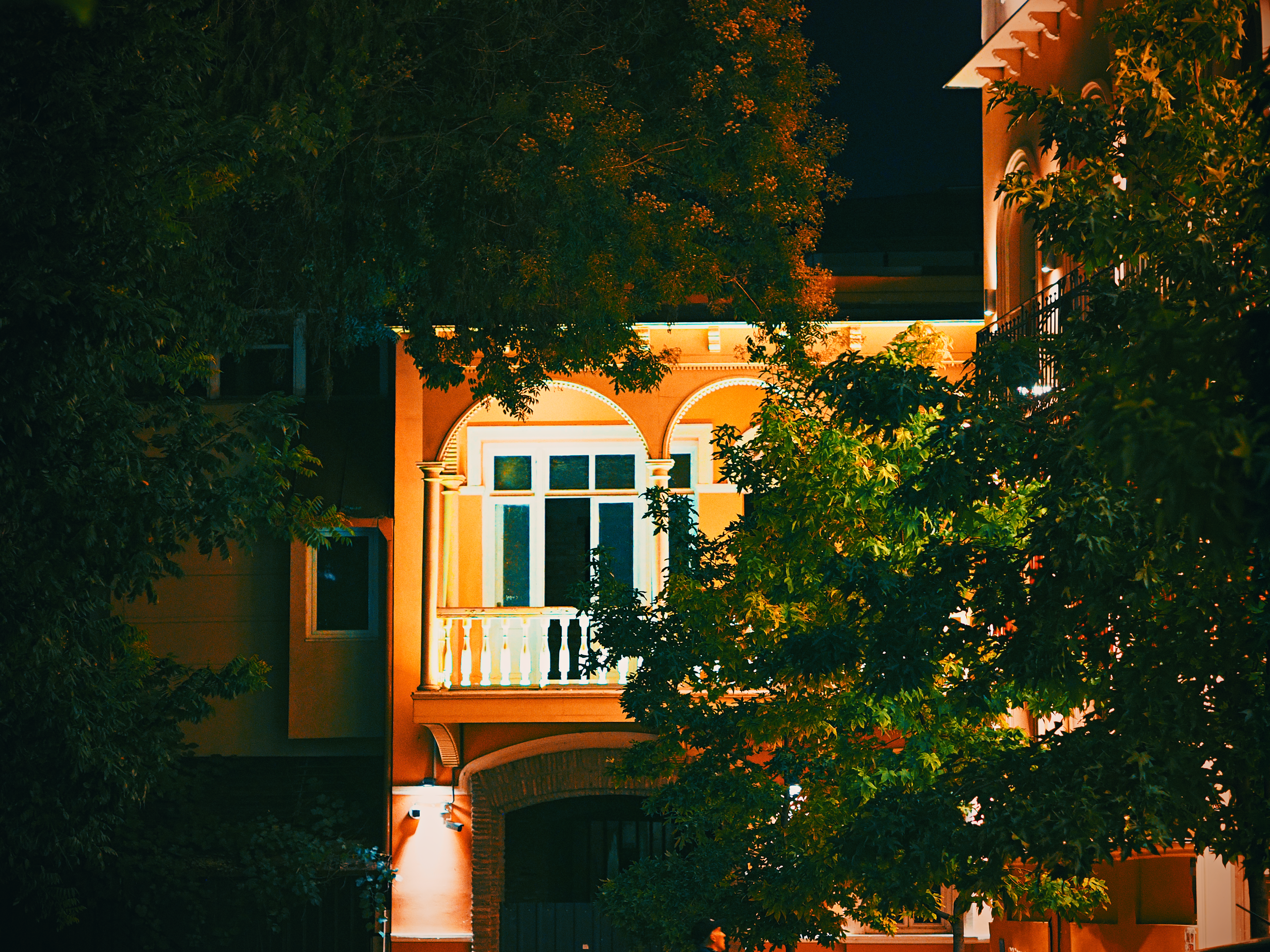 Beautifully lit house surrounded by trees, creating a warm night ambiance.