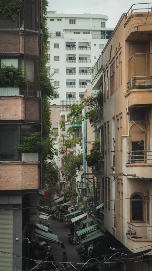 Free A bustling alleyway surrounded by tall, close-knit buildings in an Asian city. Stock Photo