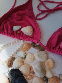 Vibrant pink bikini with seashells and pearls evokes a summer beach vibe.