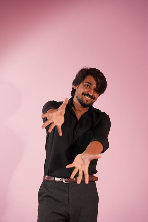 Free Smiling man in black shirt reaching out against a pink background. Stock Photo