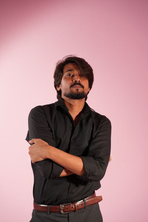 Free Portrait of a confident man with crossed arms against a pink background, expressing strength and determination. Stock Photo