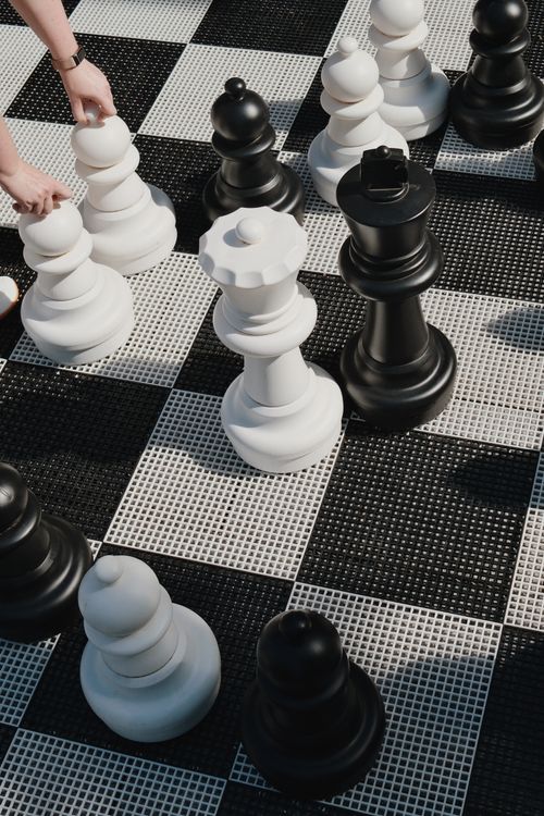 Free Hands moving giant chess pieces on an outdoor checkered board. Stock Photo