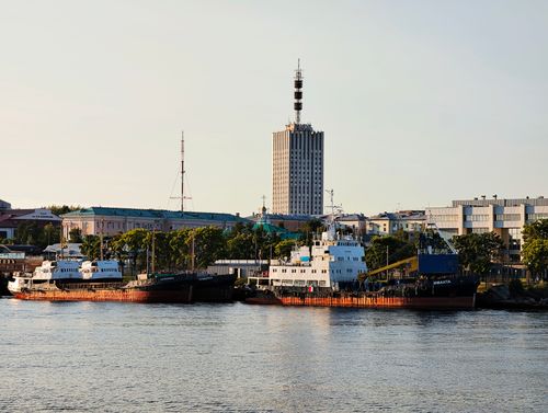 Free Ships docked at a riverside with a tall building and clear sky, captured during daytime. Stock Photo