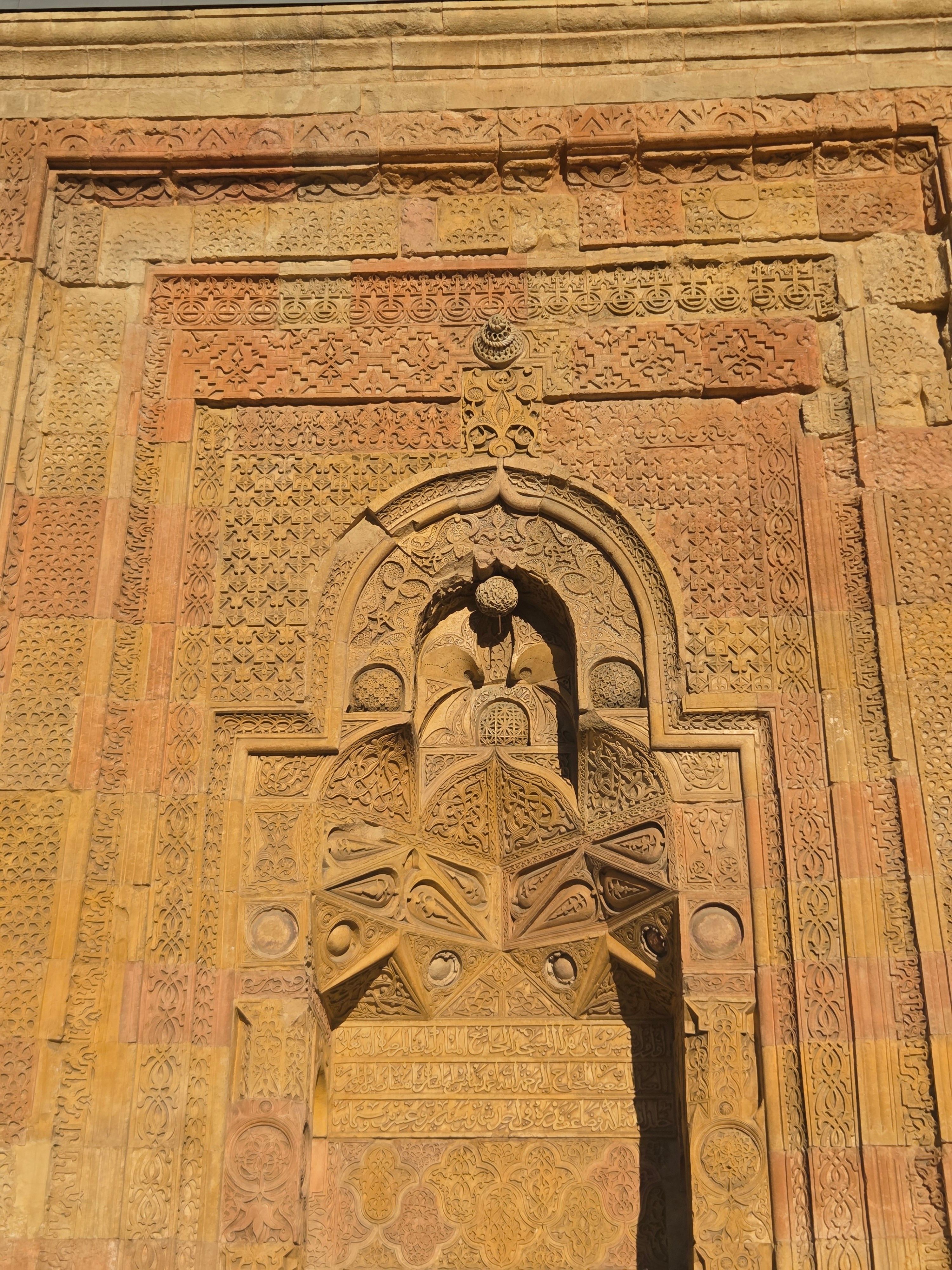 Close-up of an ancient stone archway with detailed carvings and geometric patterns.