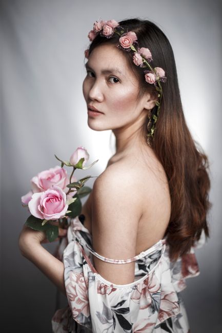 A beautiful studio portrait of a woman adorned with roses, exuding elegance and grace.