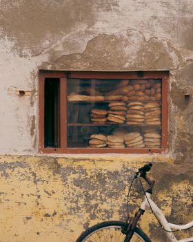 Vintage bakery shop with bread display and bicycle by a textured wall.