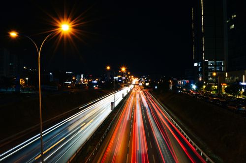 Free Long exposure photo capturing light trails on a busy highway at night with city lights. Stock Photo