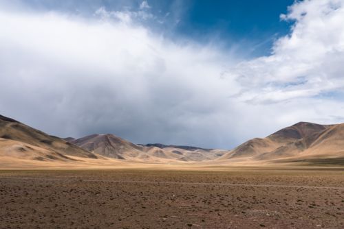 Free Expansive desert scene with mountains under a dramatic sky. Stock Photo