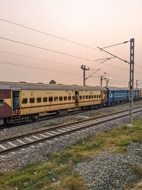 Free Indian train passes on tracks in quiet rural setting, showcasing travel by rail. Stock Photo