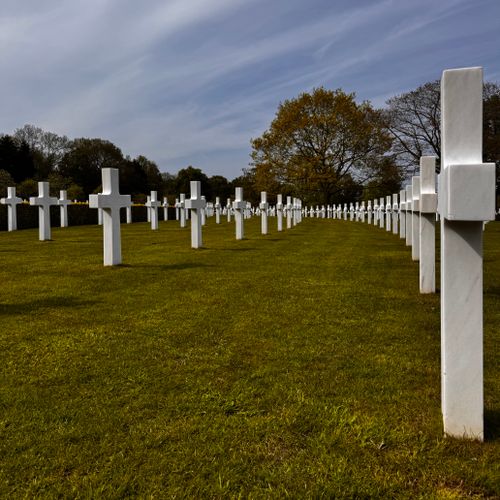 Free Serene war cemetery with rows of white crosses symbolizing sacrifice and remembrance under a cloudy sky. Stock Photo