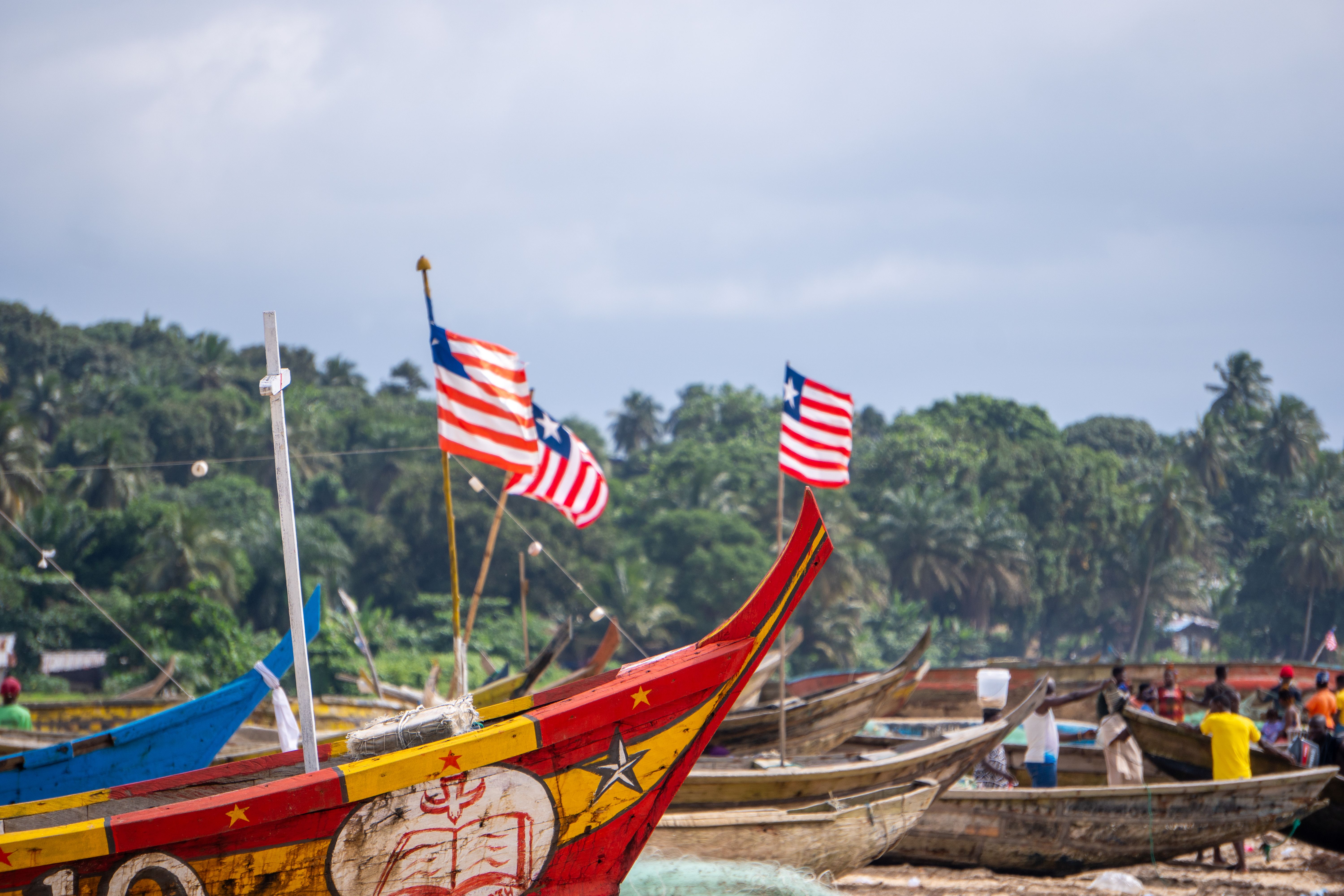 Fishing boats with Liberian flags at a village shore, reflecting local culture.