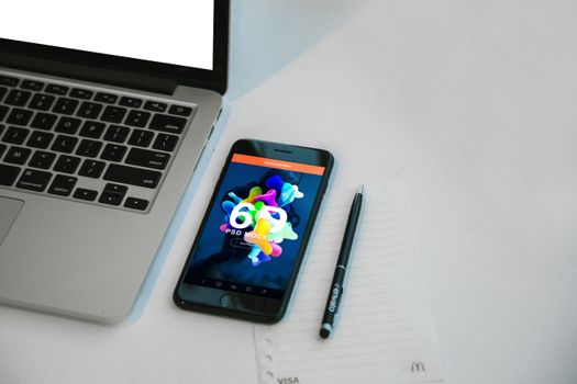 A sleek workspace featuring a laptop, smartphone, and pen on a notepad for productivity.